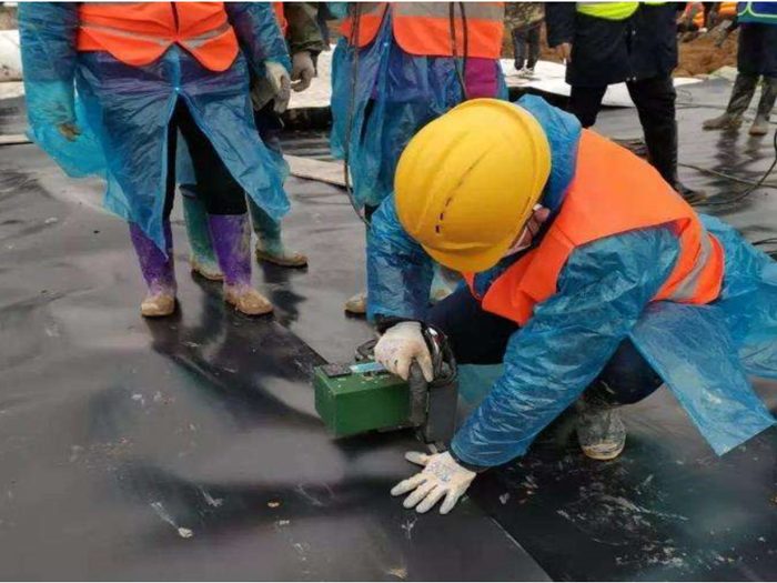 施工人员佩戴防护装备进行土工膜焊缝检测作业